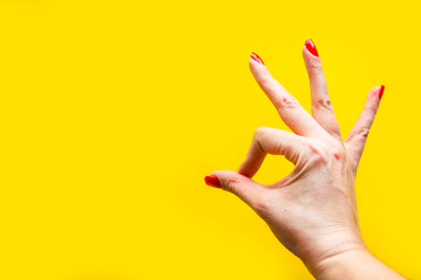 istock Woman's hand shows the OK gesture over bright yellow background. Minimal concept. Copy space for the text 1217950372