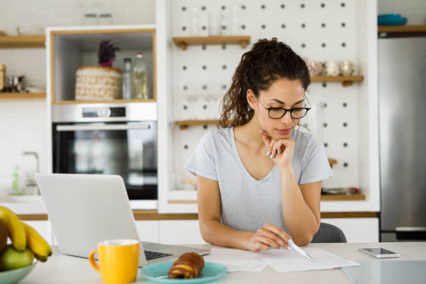istock Woman working at home and using laptop computer in the kitchen 1217951577