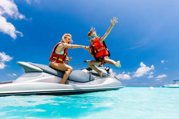 Photo of Happy single mother and son having fun on jet boat at sea.