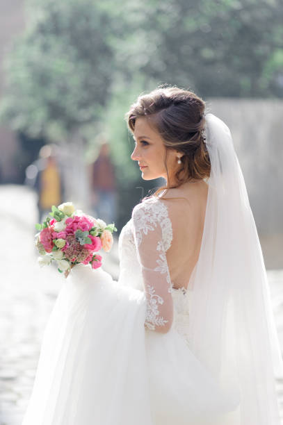 Portrait of a young beautiful bride in the old city. In the hands of a girl holding a wedding bouquet. stock photo