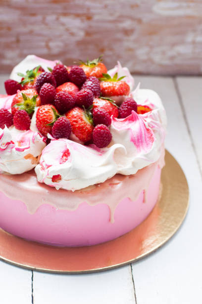 istock Pink cake with meringue, melted chocolate and fresh raspberries and strawberries. 1217951829