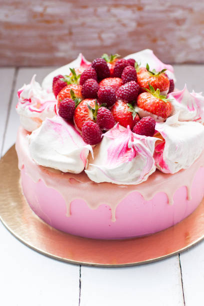 istock Pink cake with meringue, melted chocolate and fresh raspberries and strawberries. 1217951852