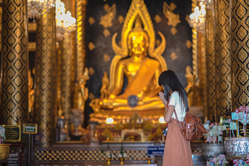 Woman traveller pay gentle respect to the buddha statue in the temple, praying respect for a better life forward, Buddhist New year, \