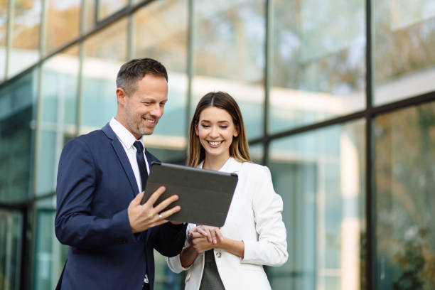 istock Two business people discussing work on tablet computer outdoors 1217953158