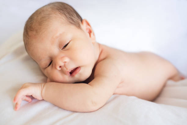 istock Newborn baby boy lying and sleeping on white bed at home 1217953446