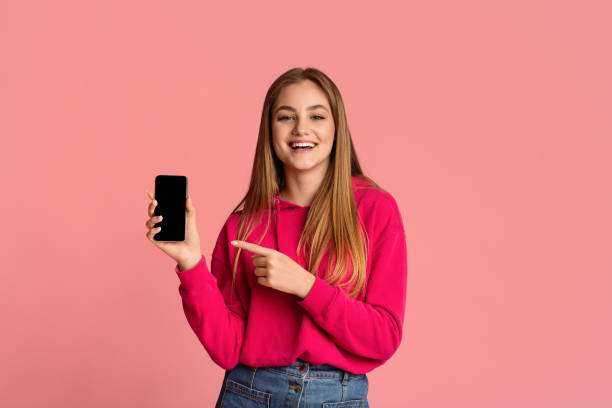 istock Girl points to smartphone with blank screen 1217959402