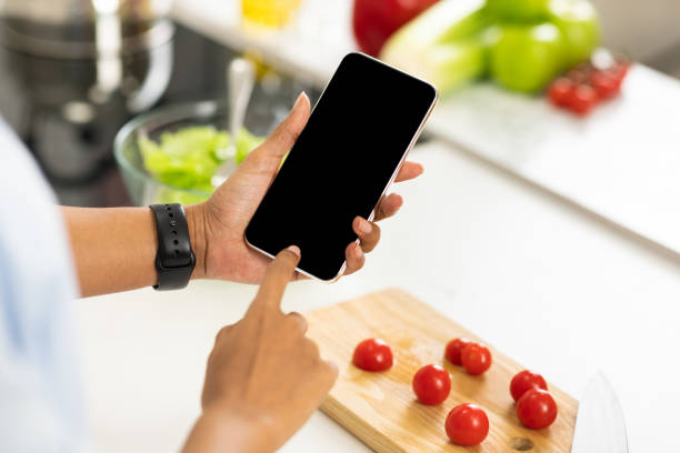 istock Black girl using smartphone with blank screen in the kitchen 1217960468