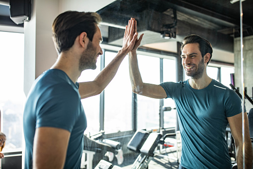 Reflection in a mirror of happy man giving himself high-five in a gym.