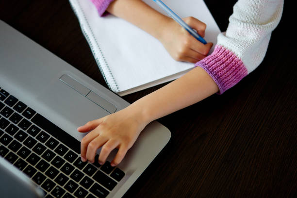 istock Unrecognizable schoolgirl studying at home with a notebook and doing school homework. 1217962192