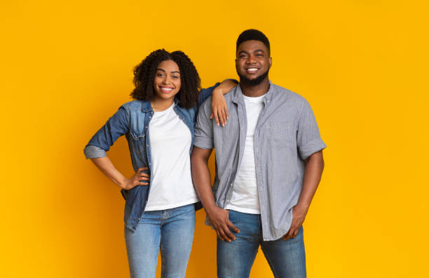 istock Cool Millennials. Attractive young black couple posing together over yellow background 1217962960