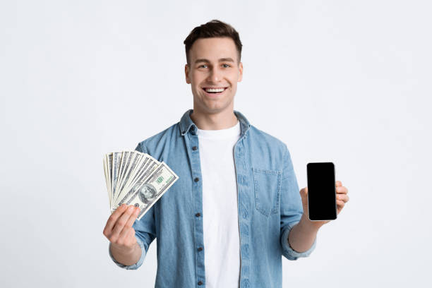 istock Man holding money and smartphone in hands 1217963942