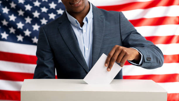 istock Voter pulls vote ballot. USA flag on background 1217964919