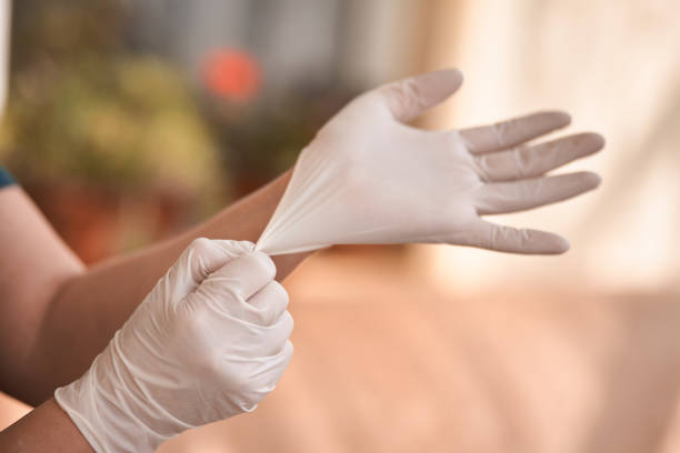 Female surgeon or nurse wearing a sterile suit putting on sterile rubber gloves to perform a surgery, Hand wearing a surgical gloves before starting the operation, Step by step procedures.
