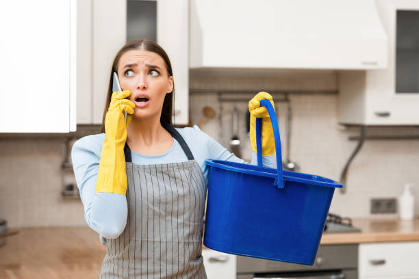 istock Scared young woman calling plumber holding bucket 1217966447