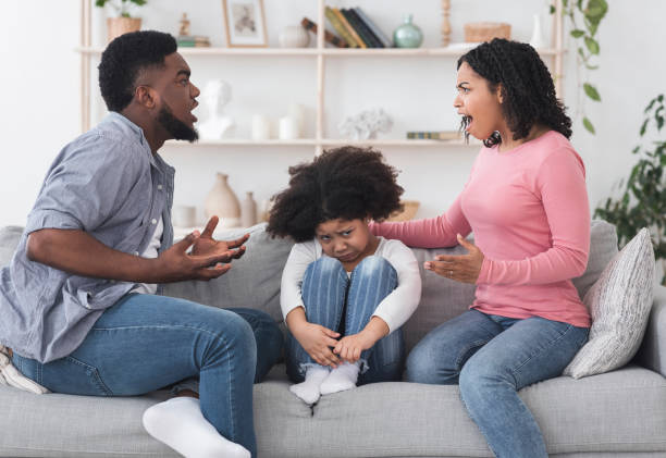 molesta niña afroamericana sentada entre los padres peleando en el sofá - surprise shouting child black and white fotografías e imágenes de stock