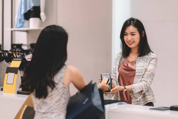 customer making credit card payment at cashier counter in clothing store at shopping mall - clothing store paying cashier credit card imagens e fotografias de stock
