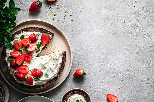 Top view of delicious yogurt strawberry pie with fresh strawberry and whipped cream on gray rustic table