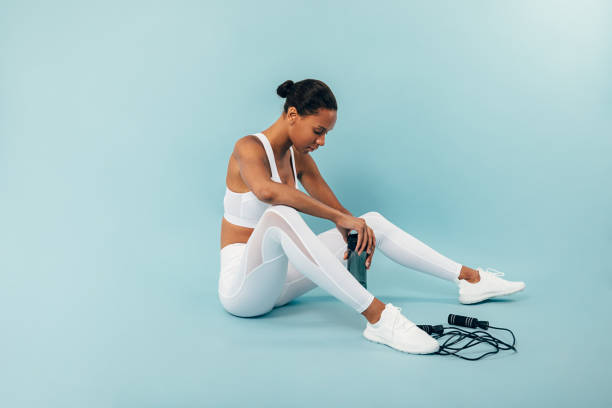 istock Tired woman sitting on blue background in studio after training 1217972108