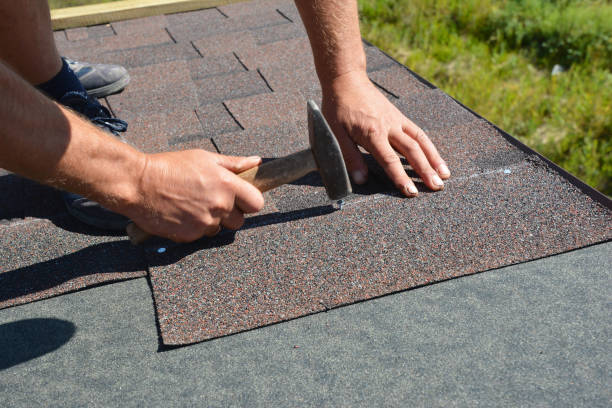 istock Asphalt shingles installation. Roofer contractor hands installing asphalt shingles on house roofing construction with hammer and nails. 1217977384