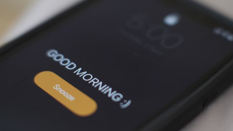 Morning alarm clock on the phone in the bed, a hand tapping snooze, close-up