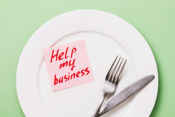 istock Note with text and a white plate with cutlery on a green background, top view. The concept of helping the restaurant business in connection with the pandemic covid-19 1217979757