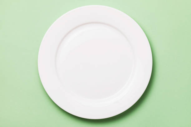 istock White plate on a green background, top view. Food background 1217979766