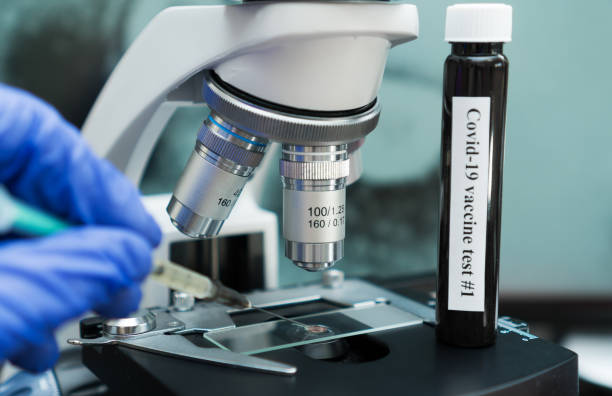 istock Virologist's hand in glove testing coronavirus vaccine under microscope. 1217982706