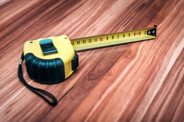 yellow construction roll measurement tape on wooden background