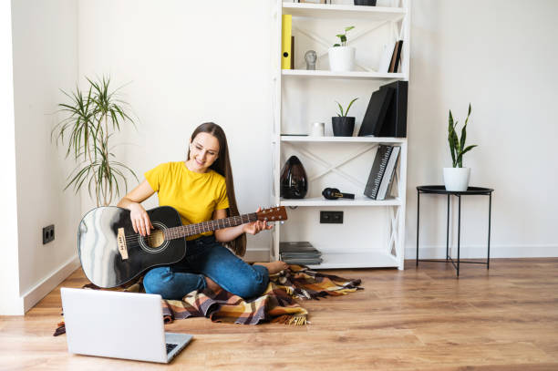 istock A woman watches video tutorial on guitar playing 1217986970