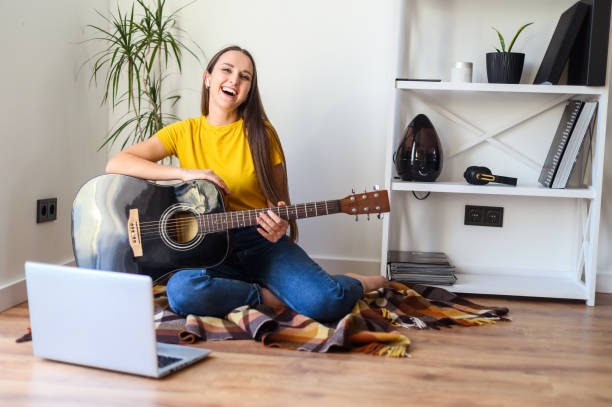 istock A woman watches video tutorial on guitar playing 1217987500