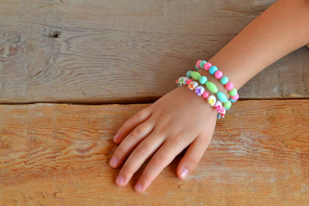 A child wears bracelets on his hands. The child hand wearing bracelets. Old wooden background Girl bracelets kids. Girl bracelets jewelry. Little girl bracelets jewelry. little girl bracelets diy. Little girl bracelets children. Little girl bracelets beads. Little girl beaded bracelets. Little girl jewelry diy. Little girl fashion accessories. Little girl fashion summer. DIY bracelets beads. DIY bracelets beads easy. DIY bracelets beads easy handmade jewelry. DIY bracelets easy beads simple baby bracelet stock pictures, royalty-free photos & images