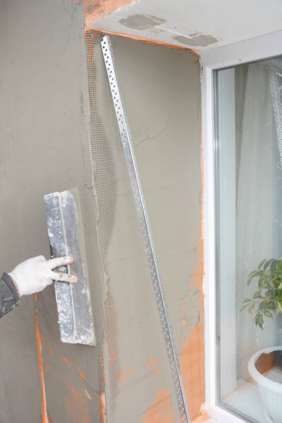 istock Building contractor plastering wall window corner with fiberglass mesh, plaster mesh after rigid insulation in window sill problem area. 1217990346