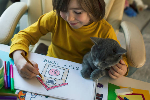 istock Little boy drawing at home while holding his cat. 1217992363
