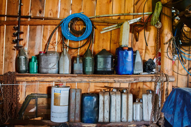 a group of old canisters and cylinders stand on shelves in a wooden shed. - rusty storage tank nobody photography imagens e fotografias de stock