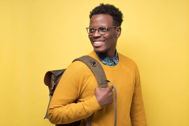 istock college student holding backpack and smiling being glad to study 1217994624