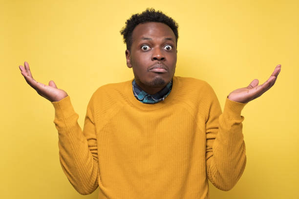 istock Young african man in yellow clothes shrugging shoulders 1217994923
