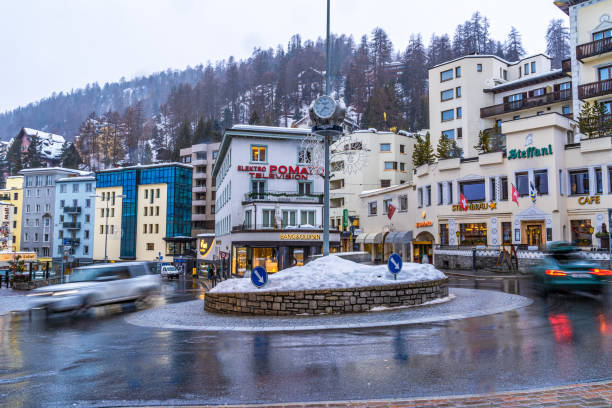 zeitraffer von autos fahren an einem kalten schneetag um den kreisverkehr in st. moritz - engadine built structure house mountain stock-fotos und bilder