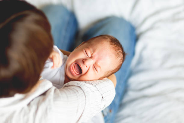 kobieta trzymająca płacz dziecka. matka pociesza swojego małego syna lub córkę. - crying zdjęcia i obrazy z banku zdjęć