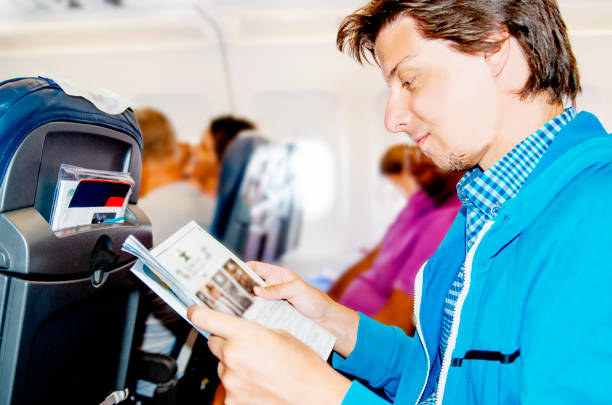 istock Young man reading newspaper in airplane during the flight. 1217997575
