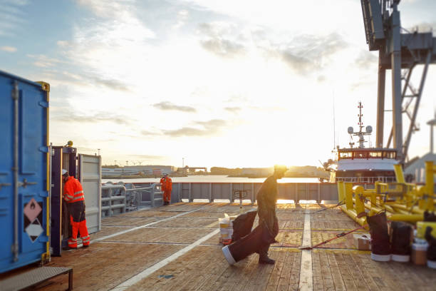 Technician pulling equipment on transfer vessel deck and preparing for offshore project in sunrise Technician pulls equipment on transfer vessel deck and preparing for offshore project in sunrise north sea photos stock pictures, royalty-free photos & images