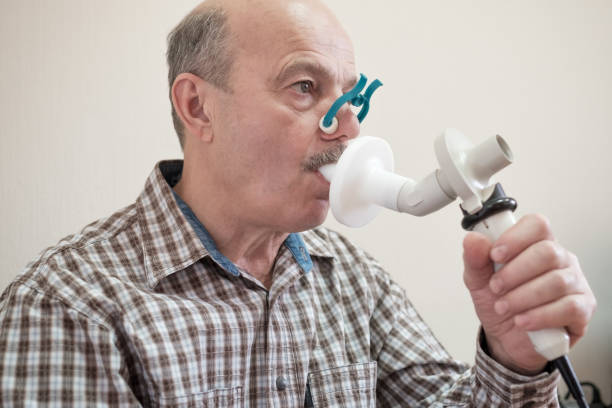 Senior hispanic man man testing breathing function by spirometry. stock photo