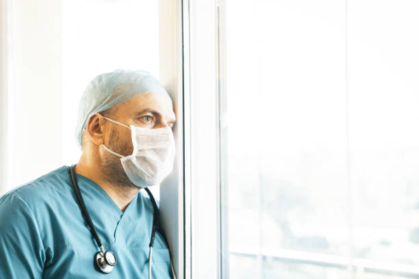 istock doctor thinking by leaning his head against the window 1218002714