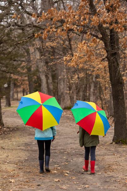 istock Two Girls Walking Through Woods With Umbrellas 1218004394