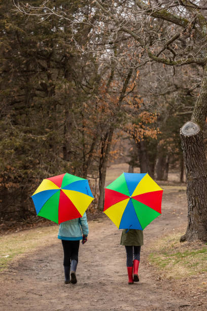 istock Two Girls Walking Through Woods With Umbrellas 1218004402