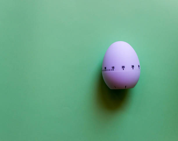istock White egg timer on green background. Happy Easter in the kitchen. Home related, home staying. Free copy space. Flat lay 1218004902