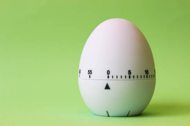 istock White egg timer on green background. Happy Easter in the kitchen. Home related, home staying. Free copy space. Flat lay 1218004903