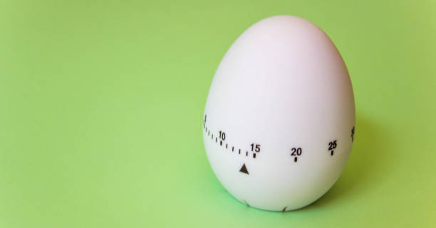 istock White egg timer on green background. Happy Easter in the kitchen. Home related, home staying. Free copy space. Flat lay 1218004971