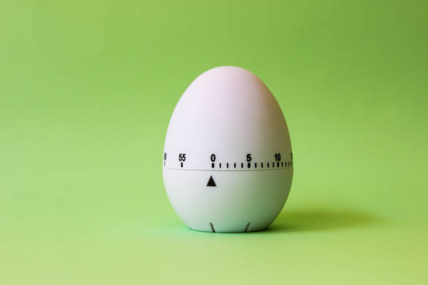 istock White egg timer on green background. Happy Easter in the kitchen. Home related, home staying. Free copy space. Flat lay 1218005588