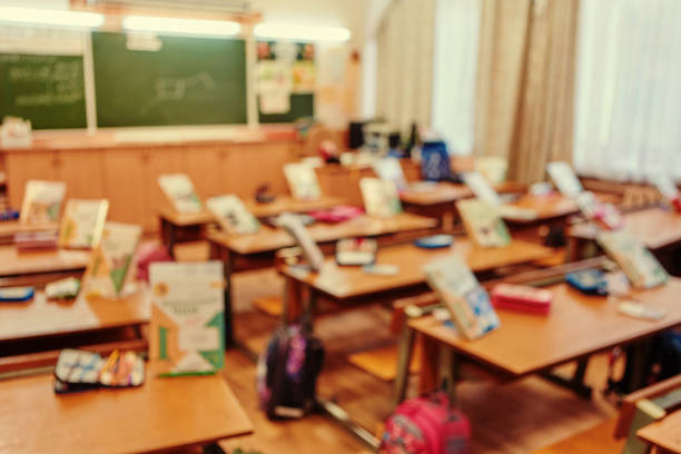 Back to school concept. Classroom in blur background without young student; Blurry view of elementary class room no kid or teacher with chairs and tables in campus
