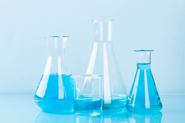 Chemistry glassware standing on a reflective surface in a laboratory.
